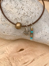 Load image into Gallery viewer, Leather Adjustable Bracelet with Dangling Silver Cross and Gold and Turquoise Colored Beads.